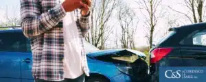 person leaning against a wrecked car on phone