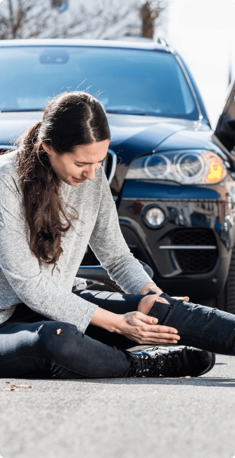An image of a woman who has been involved in an accident, clutching her leg in pain while wincing and expressing discomfort.