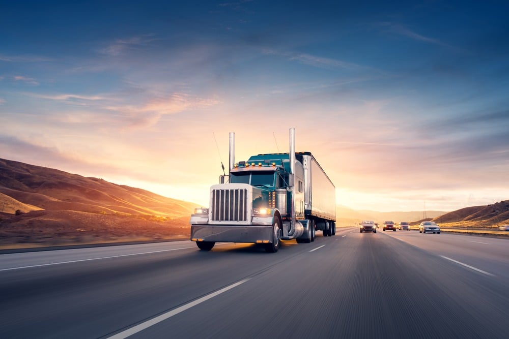 truck driving on highway with sunset in background