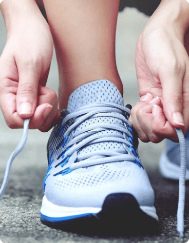 An image showing a person tying the laces of an athletic shoe, preparing to wear it for physical activity.