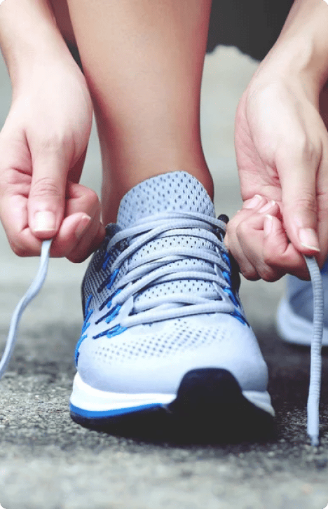 An image showing a person tying the laces of an athletic shoe, preparing to wear it for physical activity.