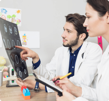 An image of a doctor and a nurse standing together and examining a medical scan or image of a patient, possibly discussing diagnosis or treatment options.