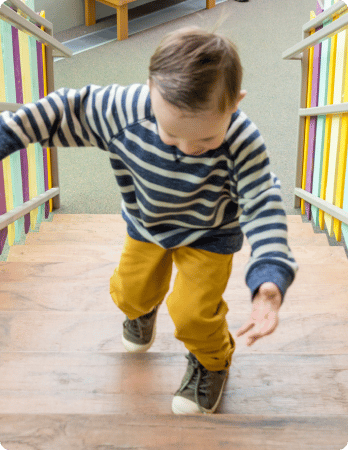 An image of a young child climbing a staircase with a happy expression on their face, indicating a sense of excitement or adventure.