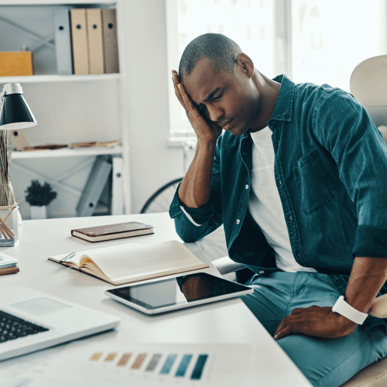 Man facing down at his office from head pains