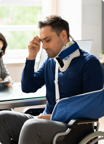 Injured man sitting in wheelchair with a neck brace and arm in a sling.