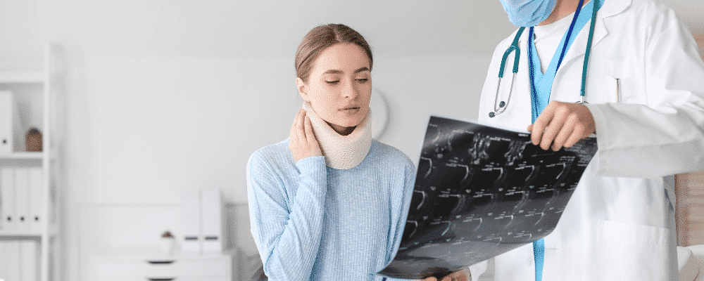 A doctor showing a patient an x-ray with neck injury involved in a car accident