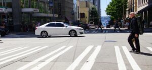 pedestrian walking across a crosswalk on a busy street
