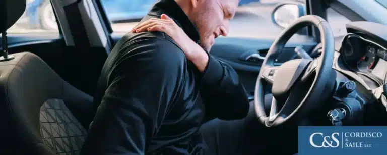 person holding onto injured back after car accident
