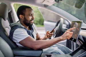 Man in Car Using Phone and Touchscreen Display